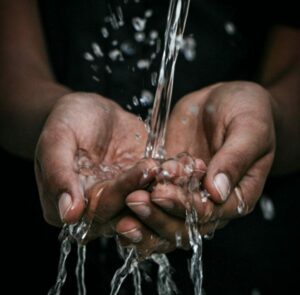 A person's pair of hands with a stream of clear water pouring into them